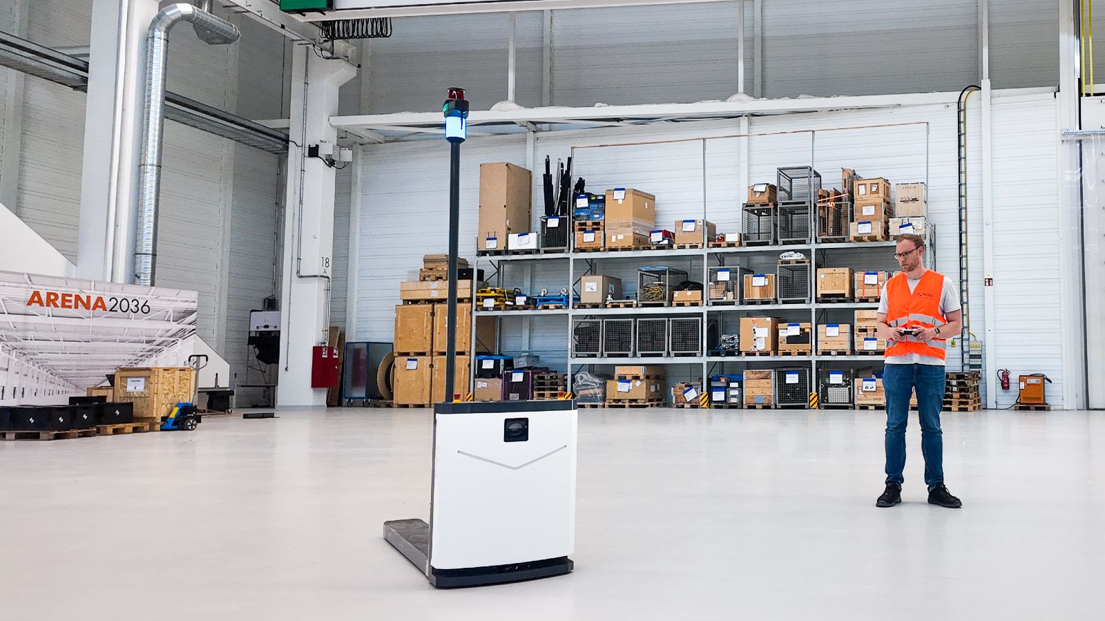 Mitarbeiter mit einem Roboter von NODE Robotics in einer groß wirkenden Halle