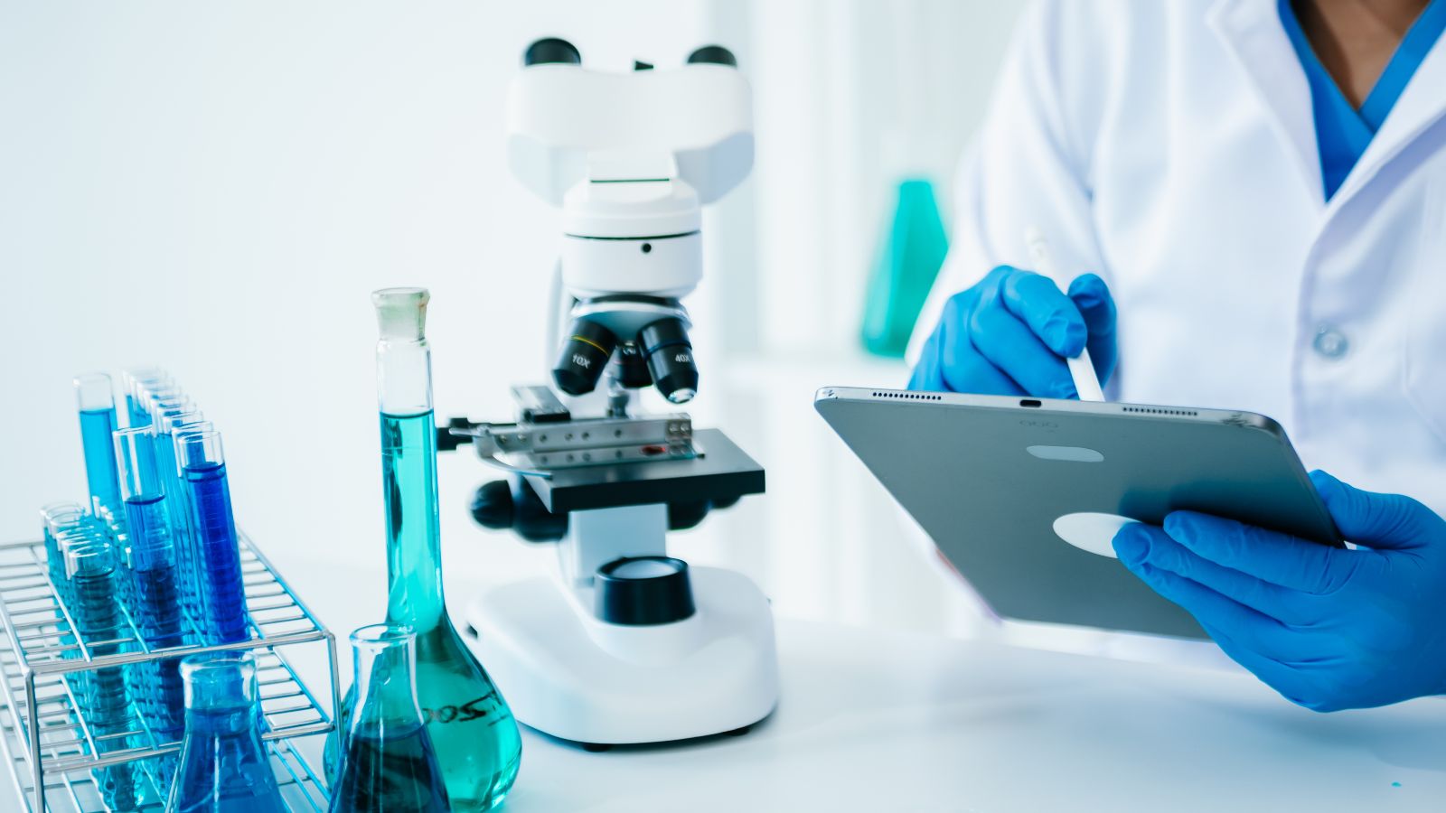 Flüssigkeiten, Mikroskop, etwas Hintergrund ein Laborant am Tablet