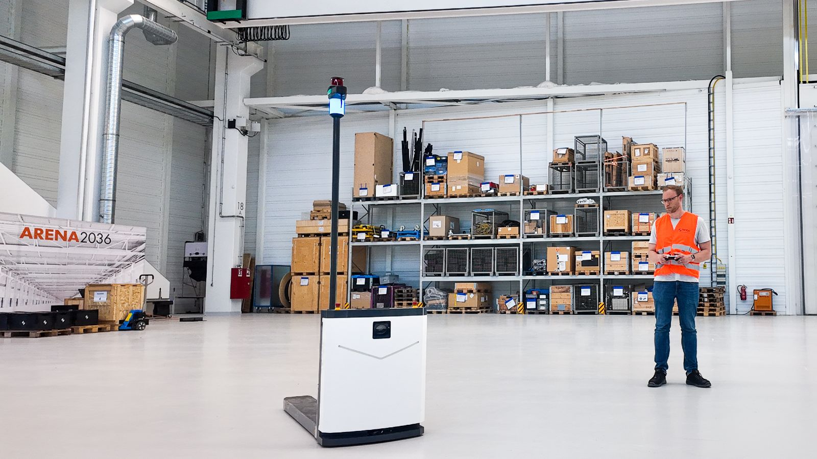 Mitarbeiter mit einem Roboter von Node Robotics in einer groß wirkenden Halle